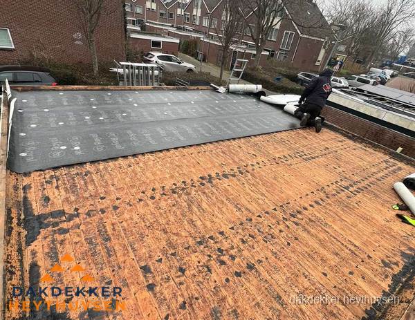 Dakdekker legt onderlaag op plat dak met houten constructie in Heythuysen
