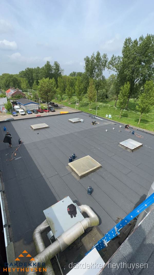 Dakdekker aan het werk op groot plat dak met bitumen in Heythuysen