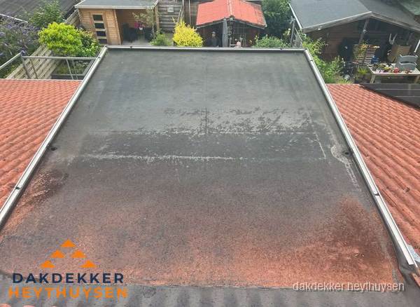 Verouderd plat dak met slijtage tussen schuine daken in Heythuysen Verouderd plat dak met slijtage tussen schuine daken in Heythuysen